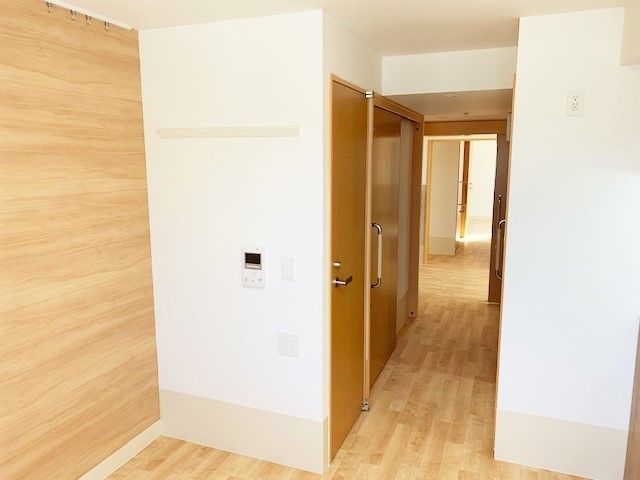 シンプルなフローリングの居室。家具などはなく、トイレの引き戸と出入り口の引き戸がある。