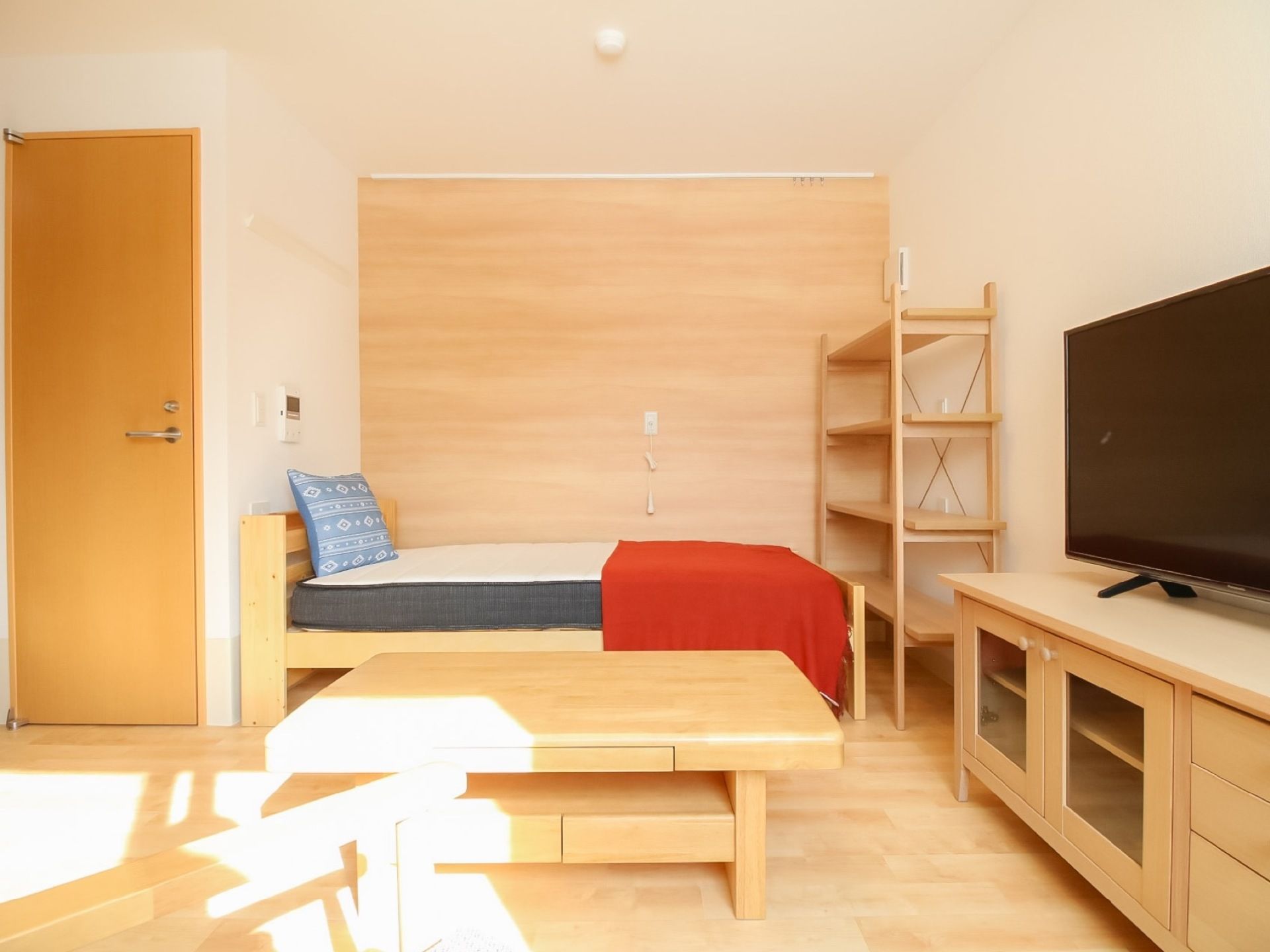 日当たりのよい明るい居室である。大型液晶テレビやベッド、飾り棚など生活最低限の電化製品や備品がそろっている。