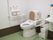 洗面台を併設した広いトイレがある。便座には背もたれや手すりが付いており、壁にはナースコールも設置されている。