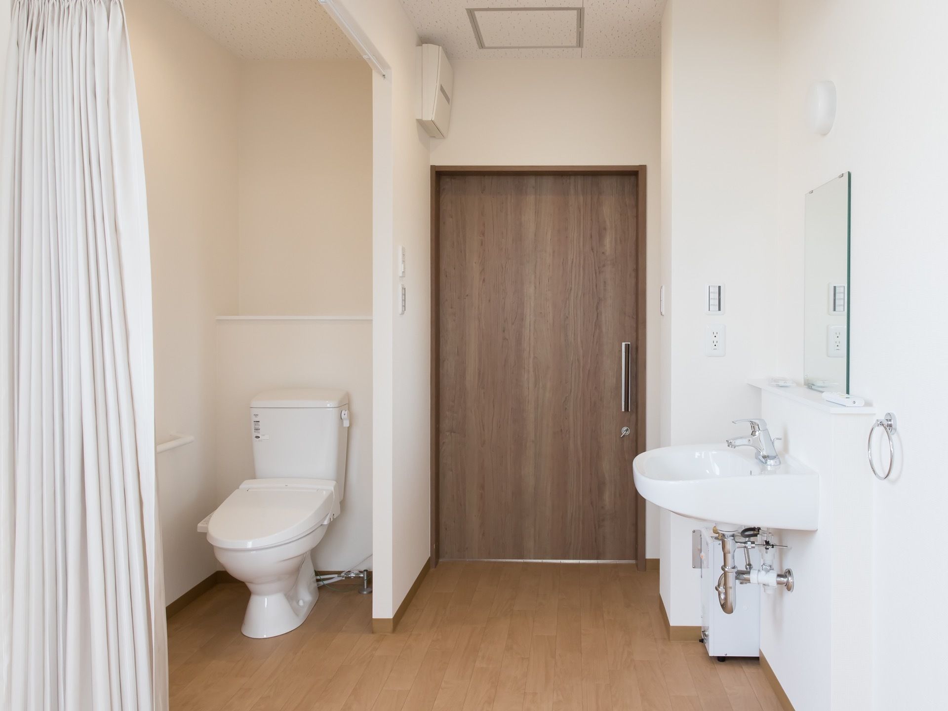 居室の入口を入ると、右手にはトイレが配置されている。ドアの代わりにカーテンを仕切りにして、車椅子でも出入りしやすくしてある。