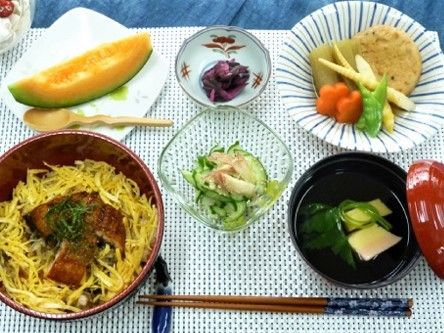 うなぎが乗ったちらし寿司、おかず、メロンなどが用意されている食事メニューの一例