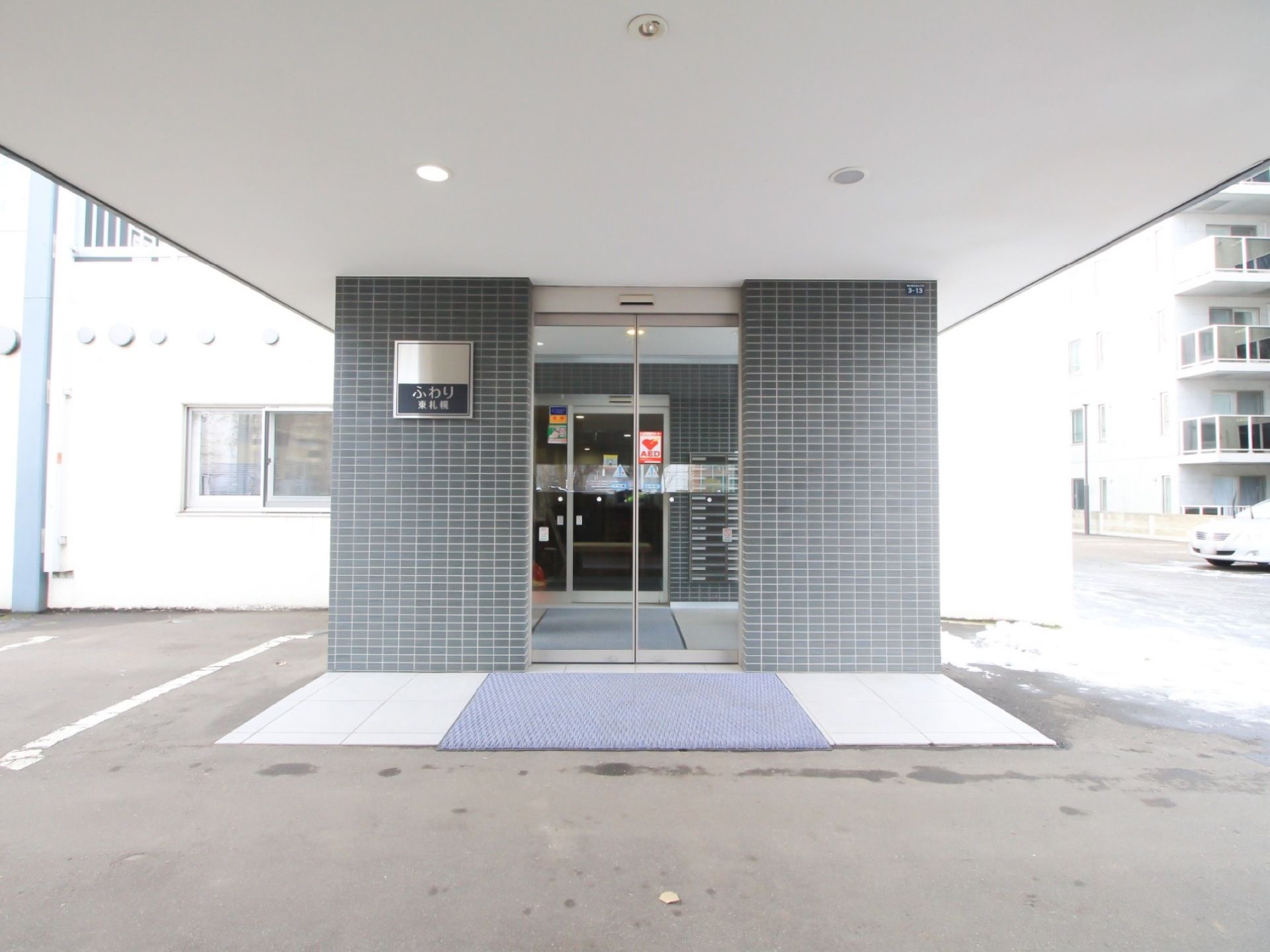 施設名を表記した看板を設置している。自動扉の入口を入ると風除室になっており、部屋ごとに郵便ポストが用意されている。