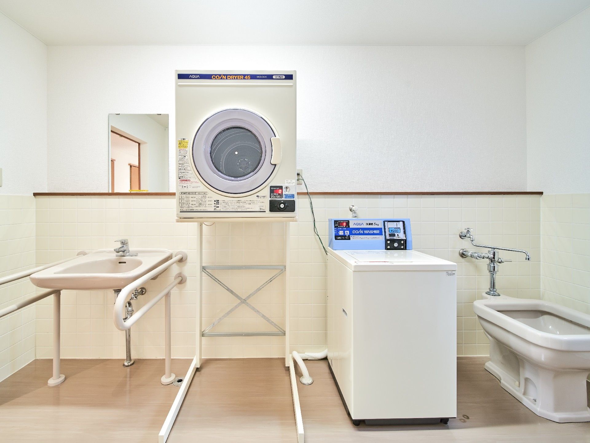 乾燥機と洗濯機がある施設内のランドリールーム。様々なタイプの洗面台