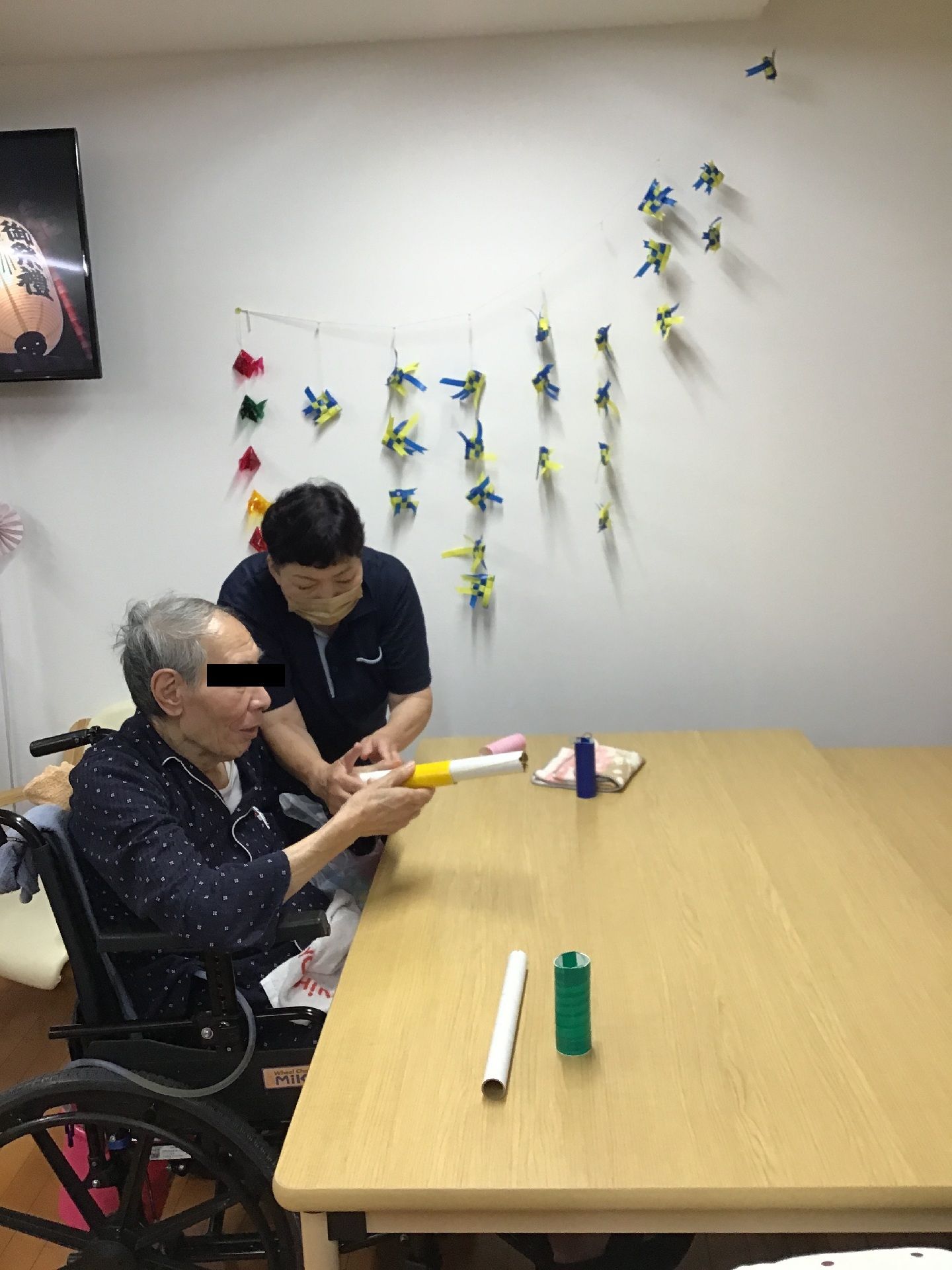 筒のようなもので遊ぶ人とそれをサポートするひと