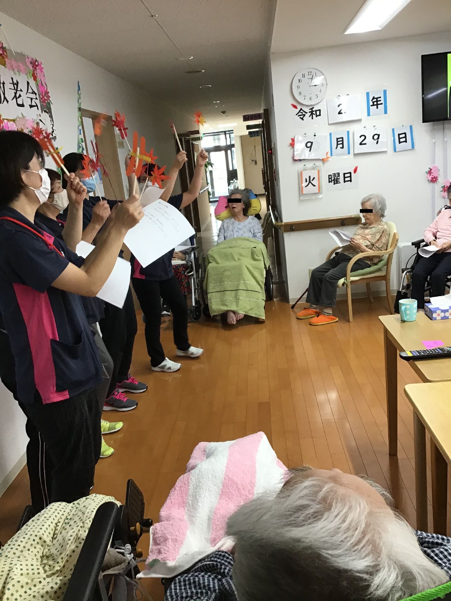 前に並んだスタッフが紅葉のようなデザインのスティックを振りかざし、利用者がそれを見ている