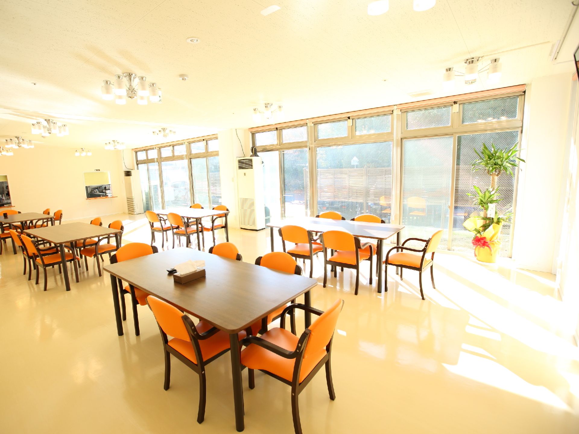 大きな窓がある広い部屋に、ゆとりをもって置かれたテーブルと椅子が並ぶ食堂