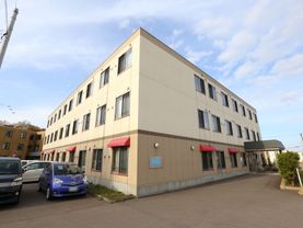 3階建てのベージュを基調とした新しい建物である。周辺は段差のないバリアフリー仕様で、駐車スペースが完備されている。