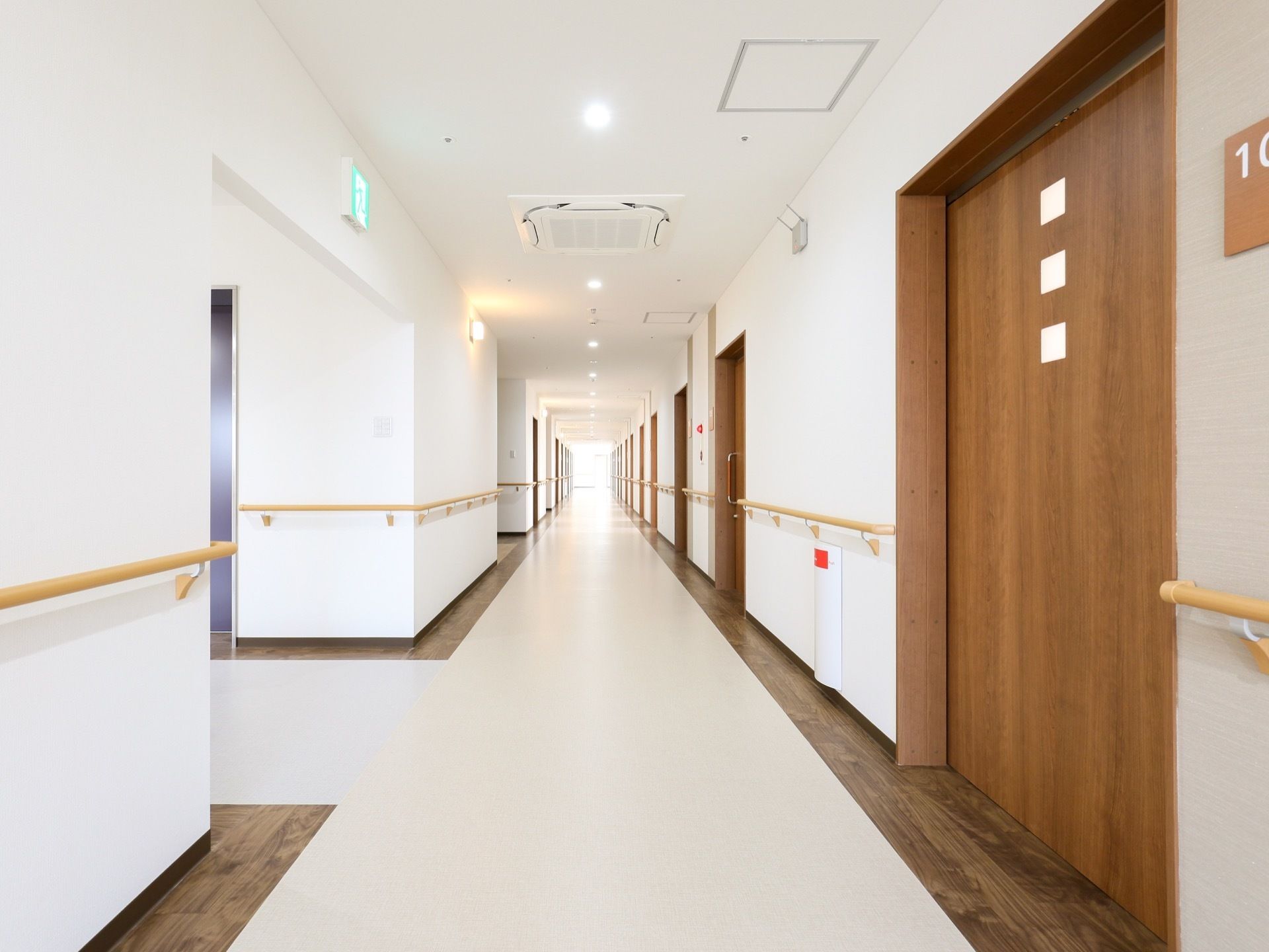 廊下の壁や天井は白色で、明るい雰囲気になっている。天井には照明と埋め込み型の空調が設置されており、壁には手すりがある。