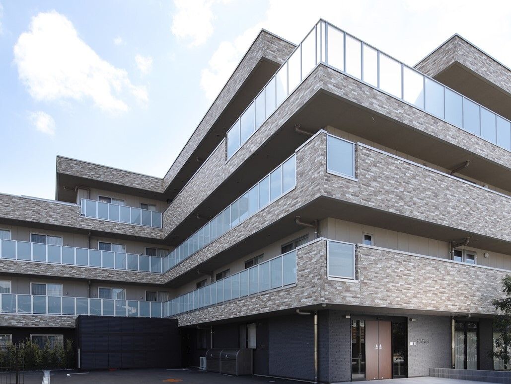 薄いブラウンカラーのモザイクタイル張りの4階建ての施設