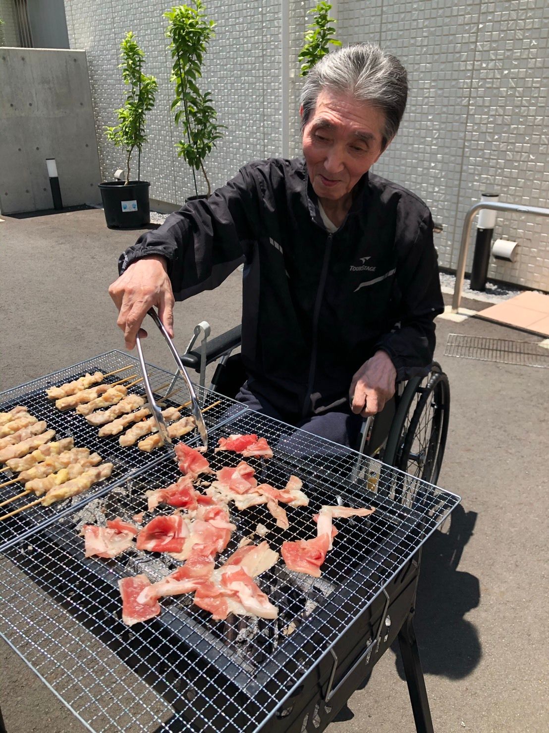 BBQをするおじいさん。足を組んで肉を焼いている