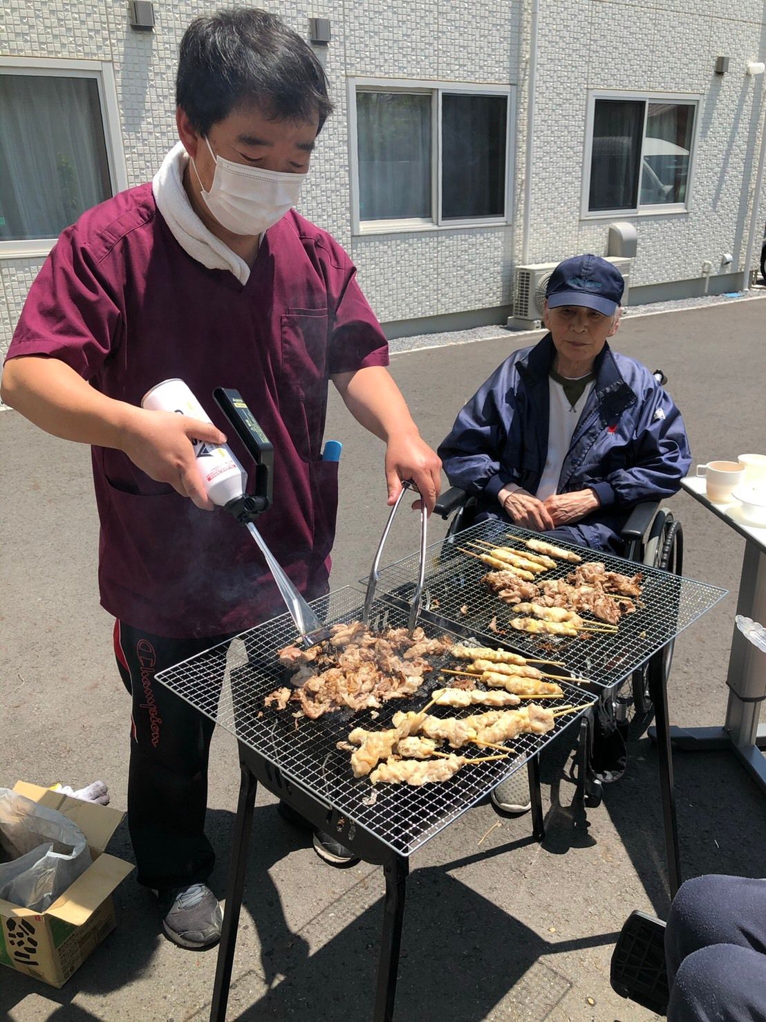 肉を焼くスタッフとそれを眺める利用者