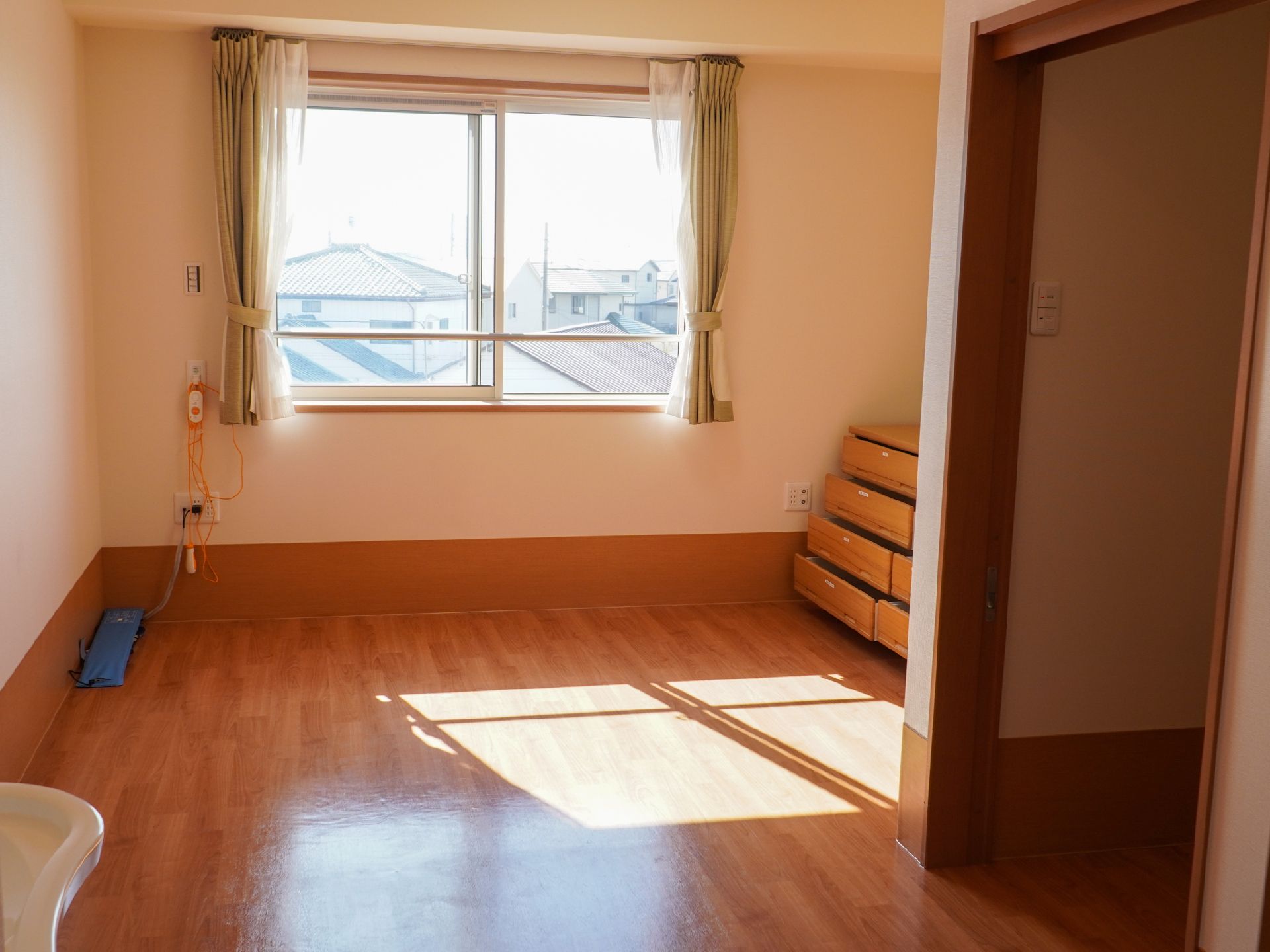 日差しが差し込み、介護ベッドが置かれている居室