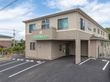 ベージュを基調とした2階建ての建物の外壁にはホーム名が書かれ、駐車場もある。