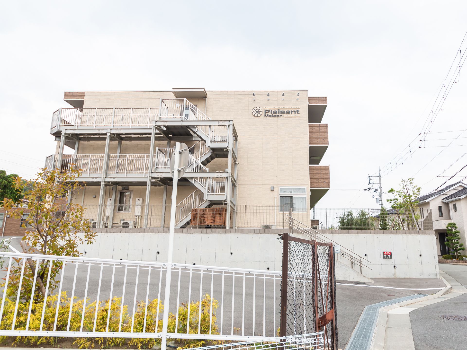 坂道の途中にある３階建てのベージュの建物