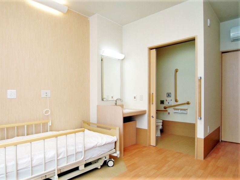 トイレは引き戸で洗面所は車いす対応、ベッドは介護用のものが置かれている。
