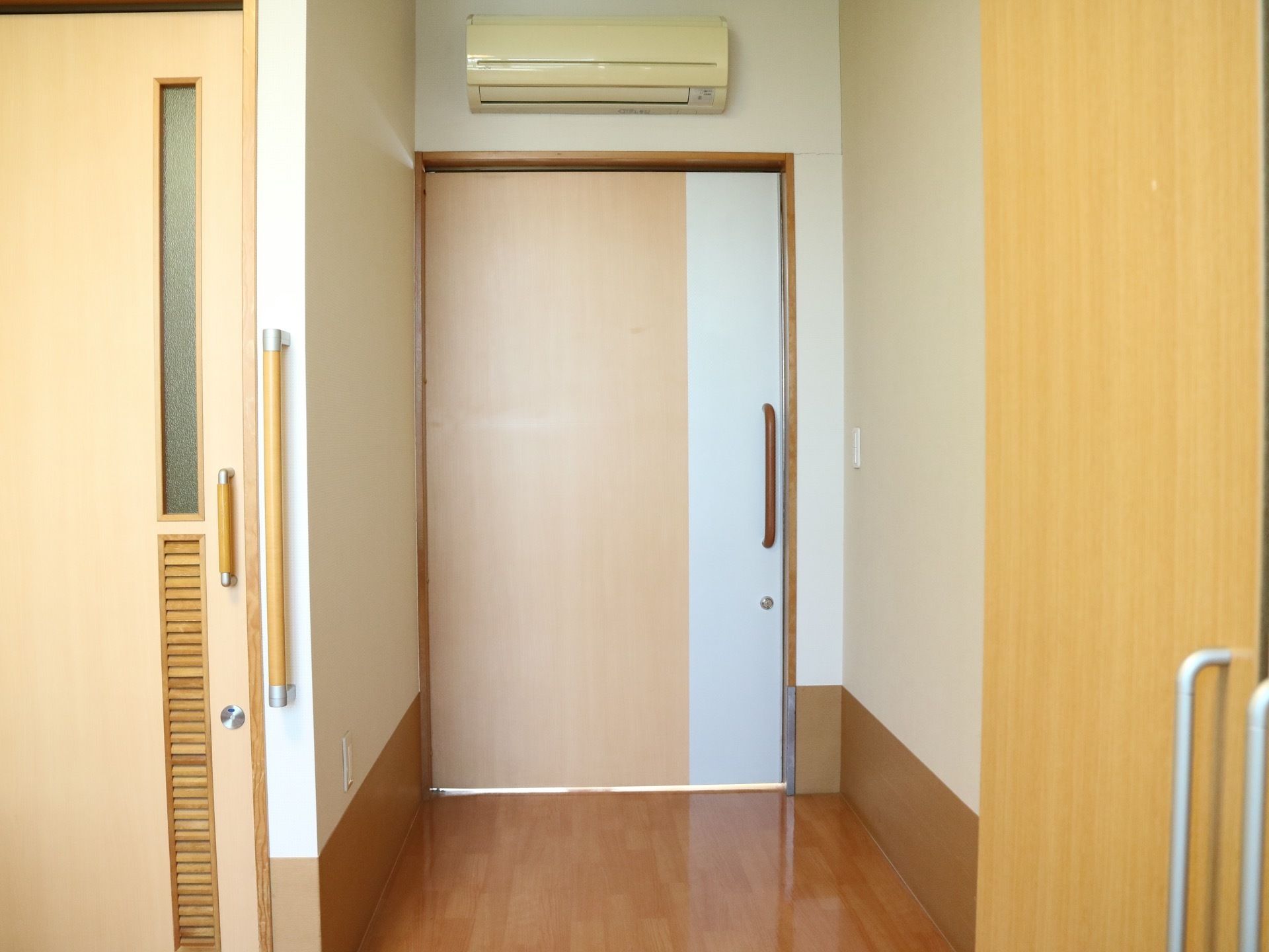 エアコンが完備されているフローリングの床の居室。扉はスライド式となっており、鍵が掛けられるようになっている。