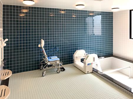ダークブルーと白のタイルががられた浴室。浴槽にはリフトが付いている。