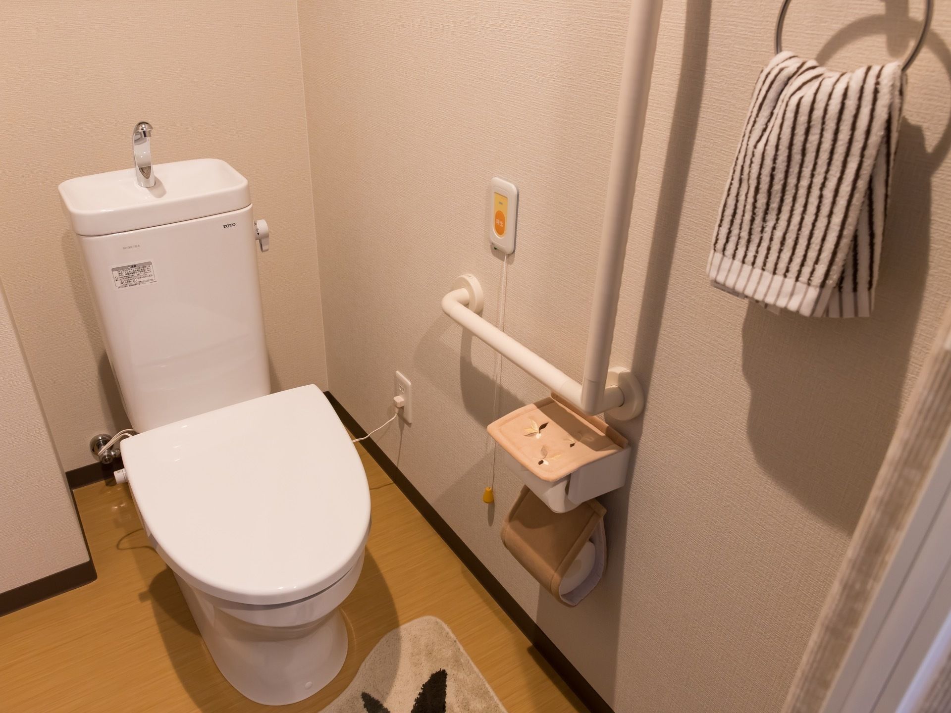 トイレ横の壁にL字型の手すりや操作パネル、ペーパーホルダーが設置されている。便器上部は、手洗い場が設けられている。