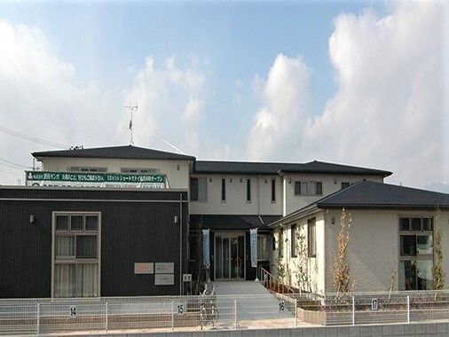 赤いトレーニング器具を引っ張りリハビリをする高齢女性と理学療法士の男性