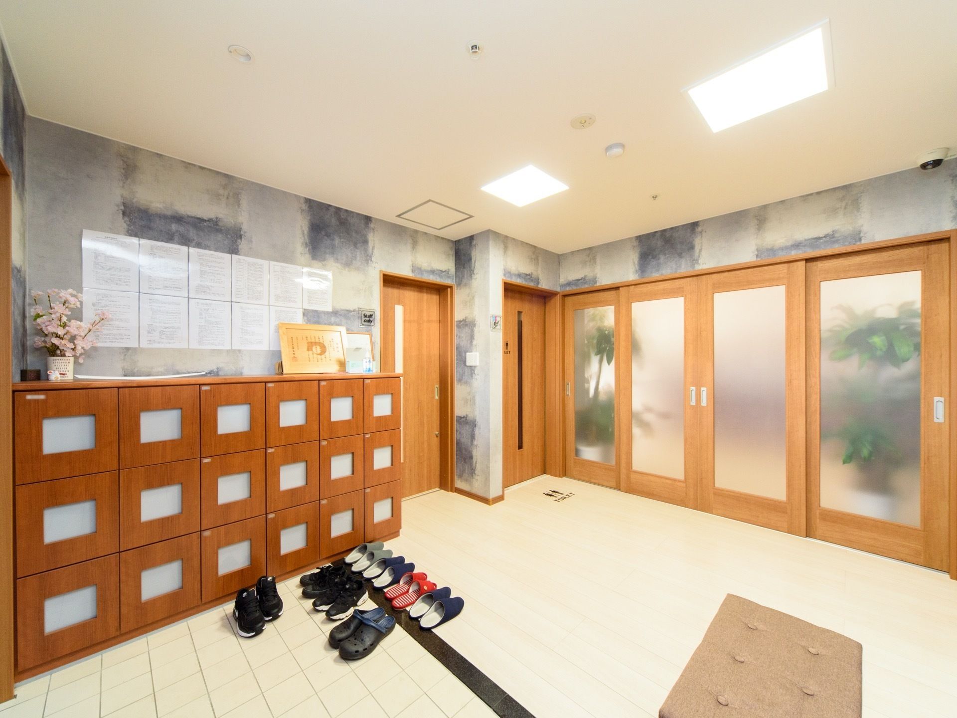 下駄箱があり、その上に花などが飾られている。手前のフラットな床に、スリッパなどが綺麗に並べて置かれている。