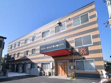 黒とオレンジの縞模様の外壁で目立つデザインの施設外観。太陽のマークが描かれている