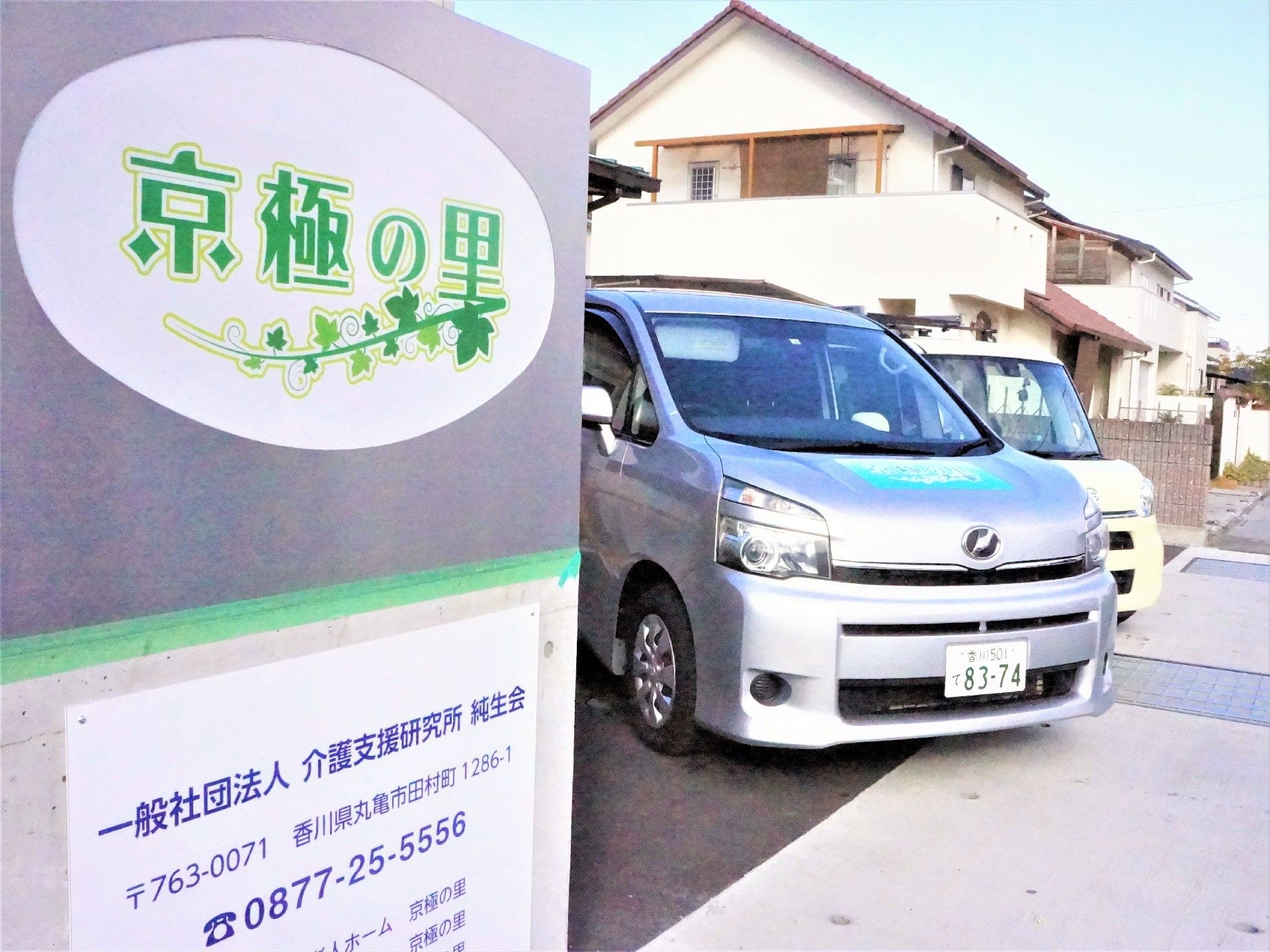 ホームの前には駐車スペースがあり、複数の車が止まっている。その横にはホーム名が書かれた看板もある。