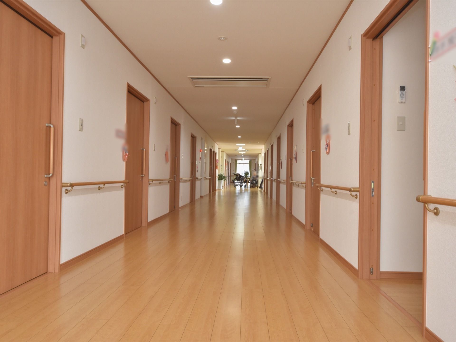 幅の広い廊下の両サイドに手すりが付き、居室のドアも並んでいる。