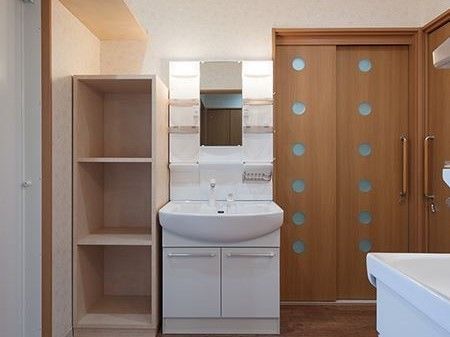 洗面所は大きく収納も多いデザイン。横にはドアと木製のカラーボックスがある。