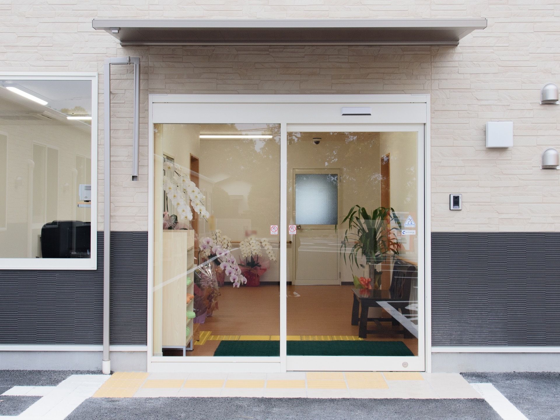 見通しの良い自動ドアの玄関がある。建物の外も舗装されて平らになっており、段差のない設計になっている。