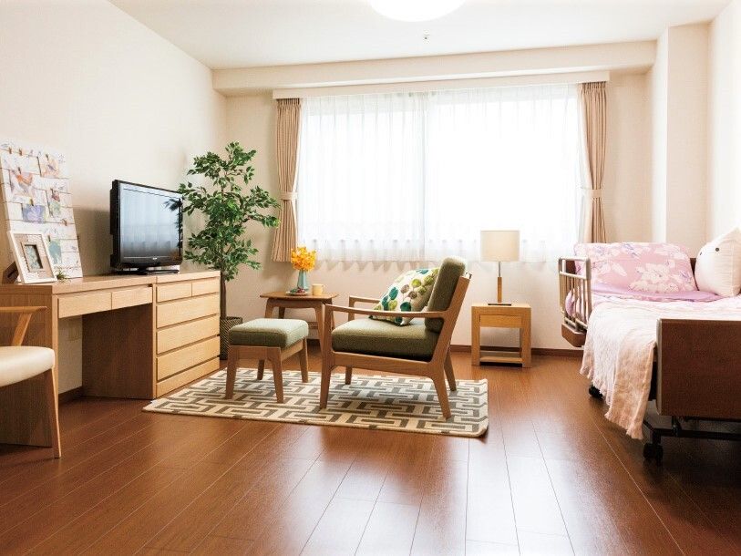 机やタンス、ソファなどが置いてある施設内のワンルームタイプのい部屋