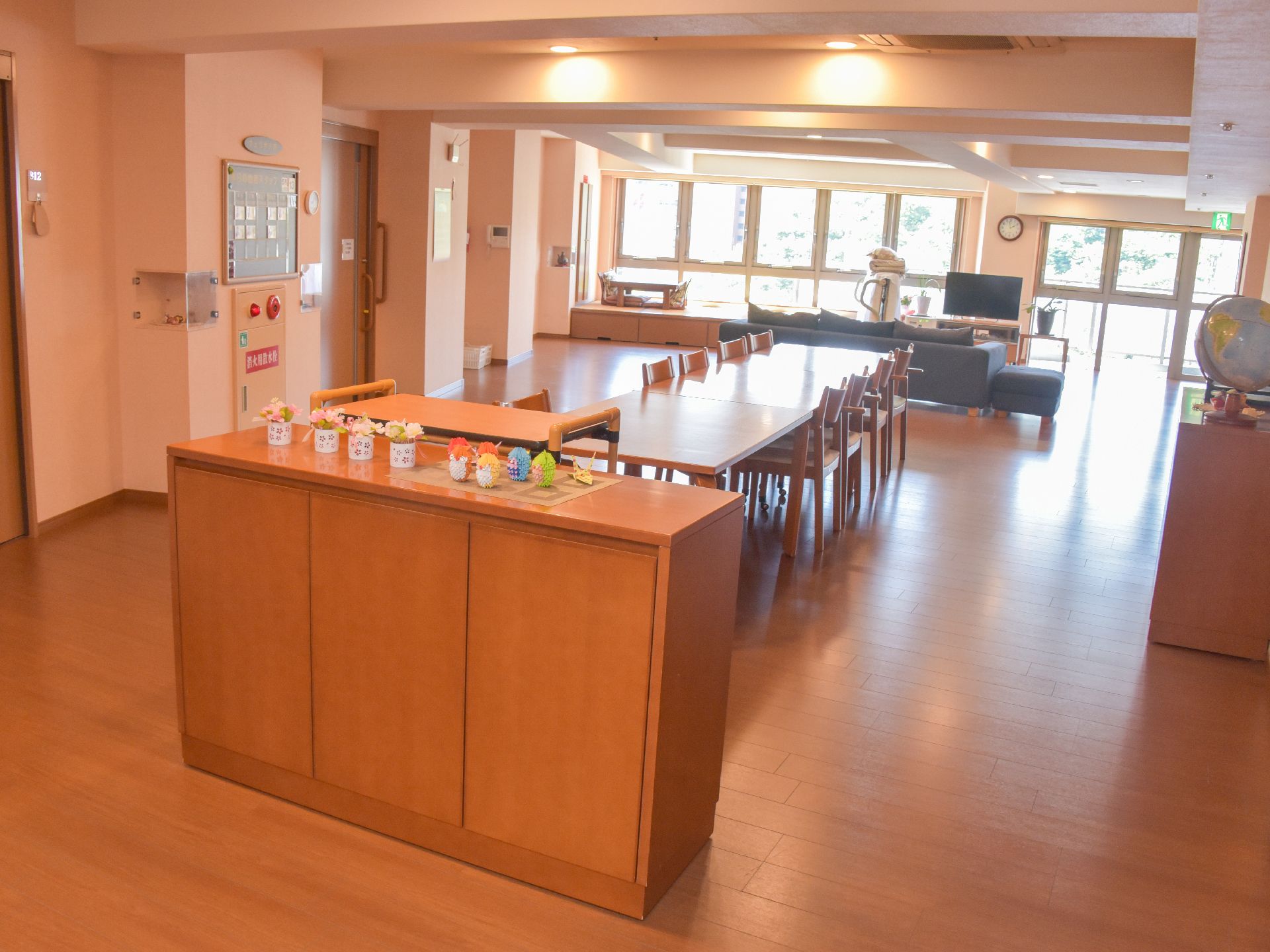 窓際にテレビとソファ、部屋の中央に食卓テーブルが設置された共有スペース