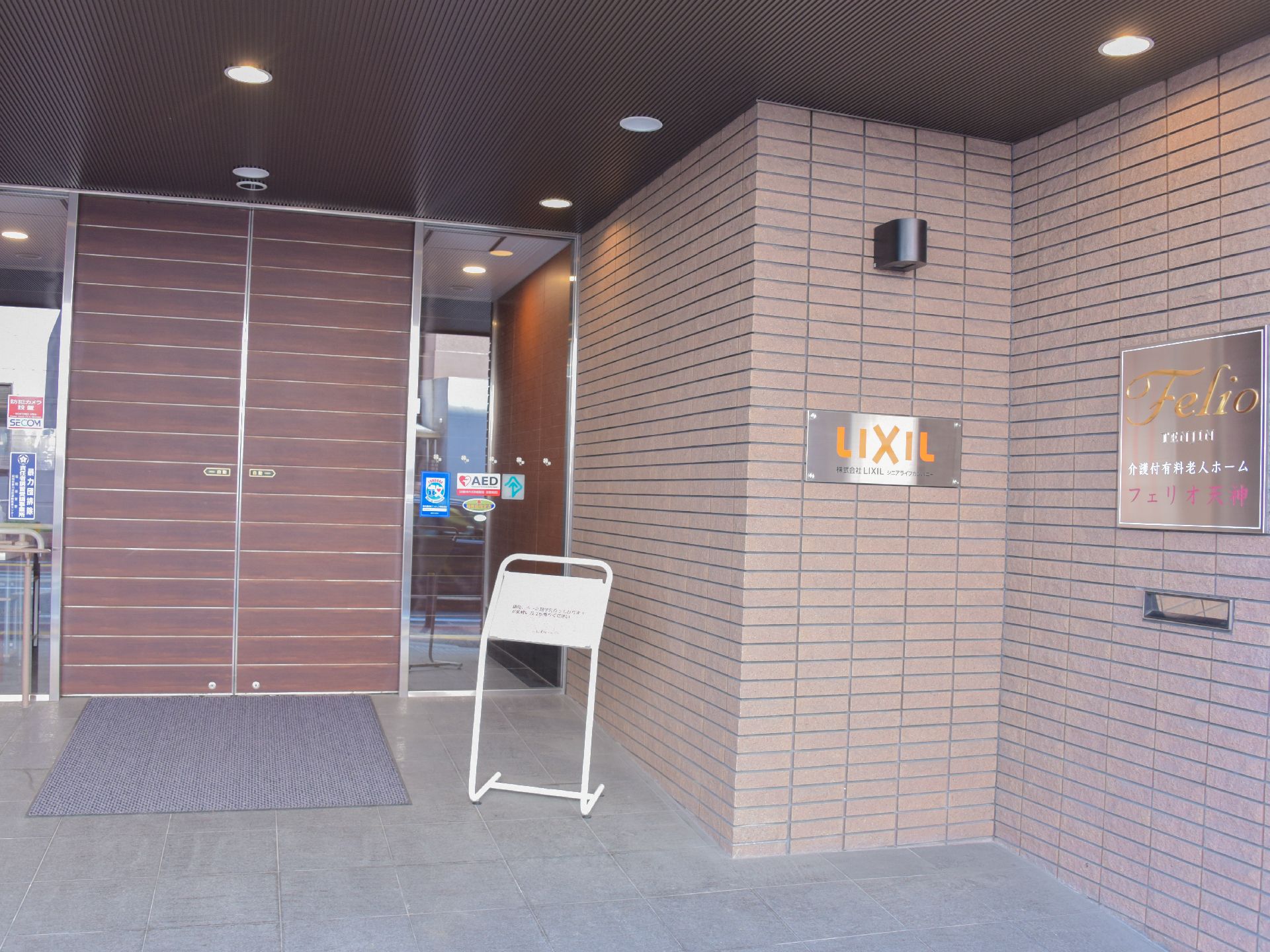 まるで新築のマンションのように綺麗な施設の建物。エントランスは自動ドアになっておりAEDの設置を現すステッカーが見える。