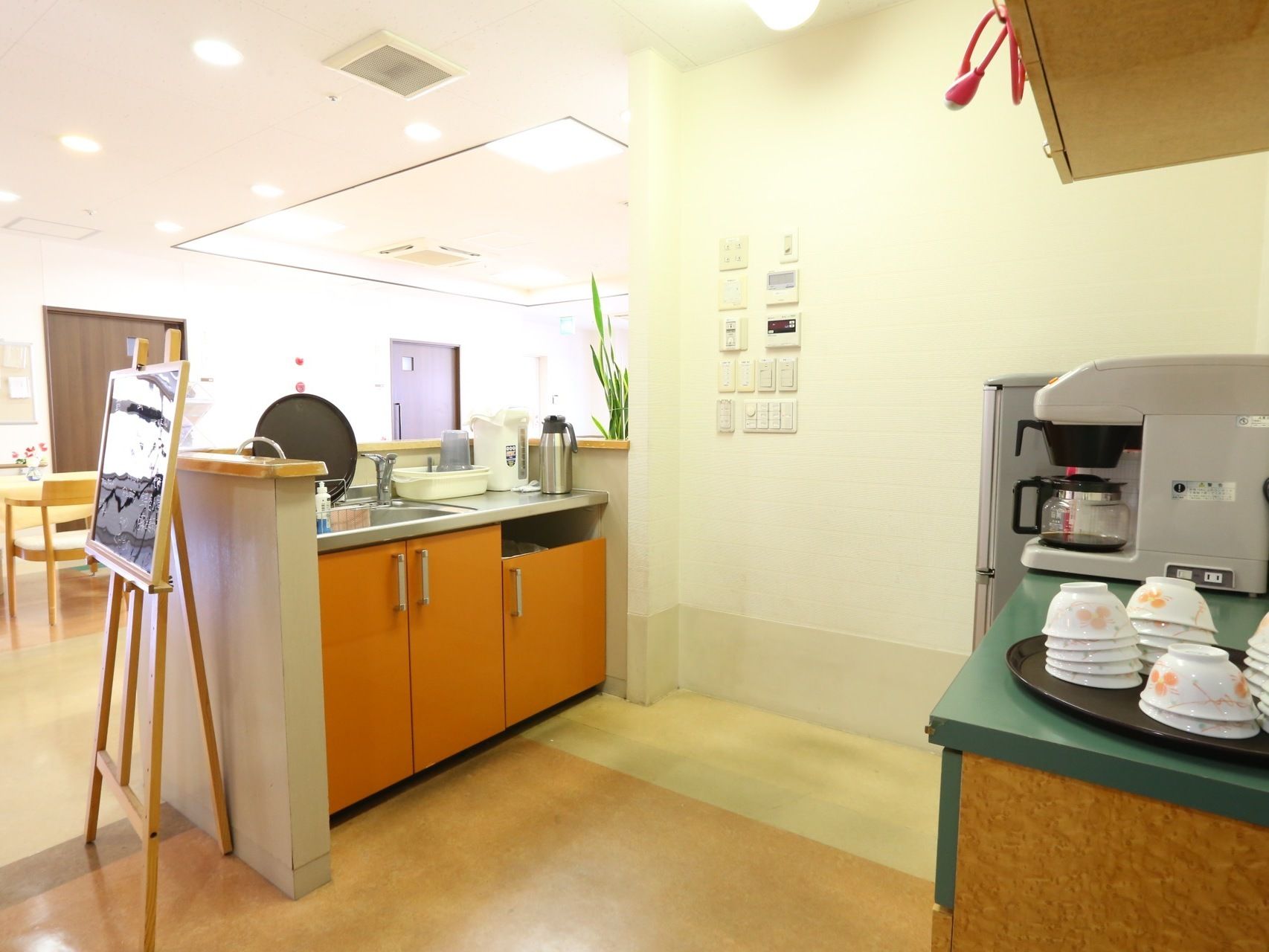 入居者様が利用する食堂の片隅にキッチンが完備されている。冷蔵庫やコーヒーメーカー、茶わん、ポットが置かれている。