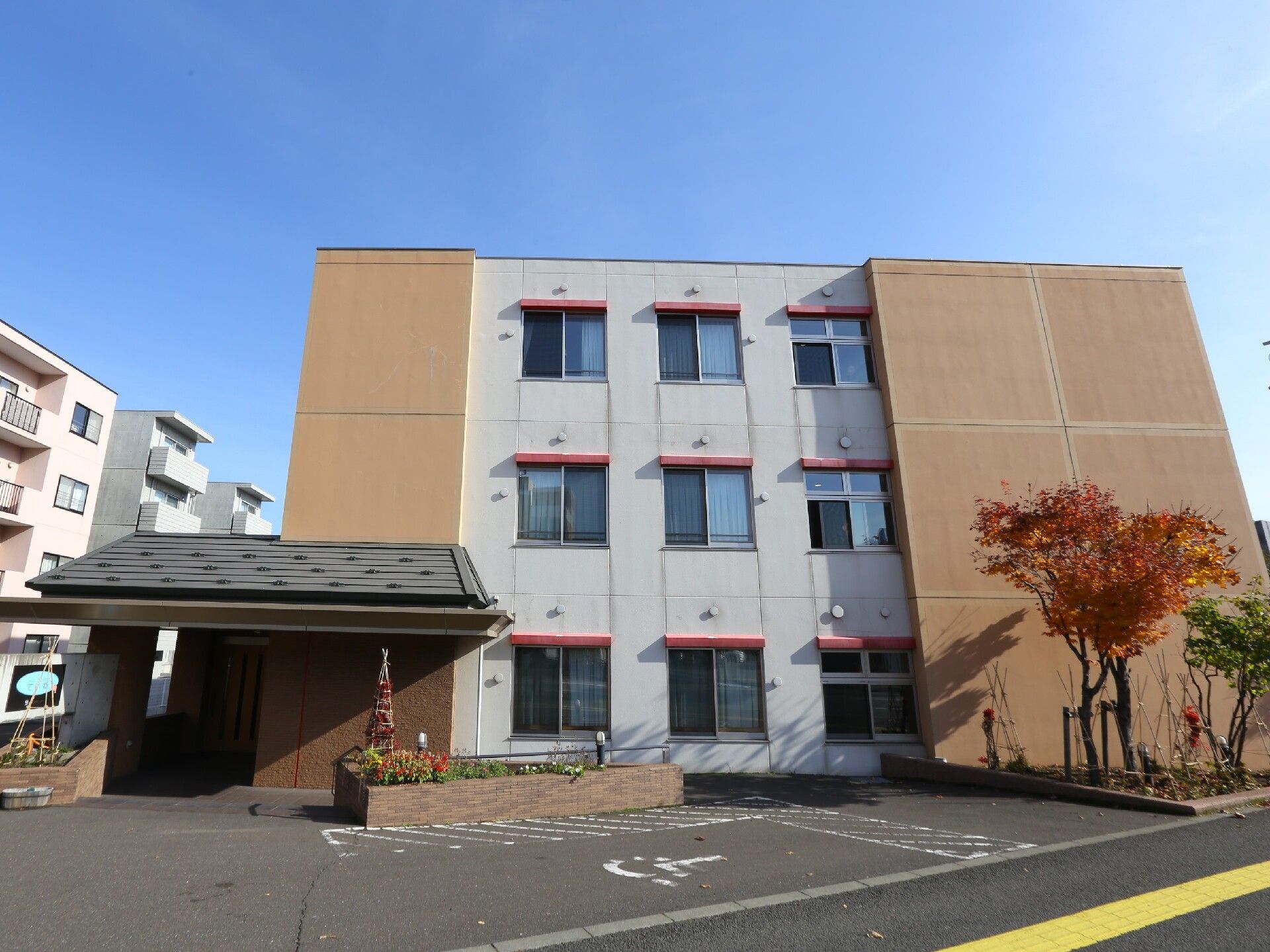 前面に駐車スペースや植え込み、花壇を設けている施設