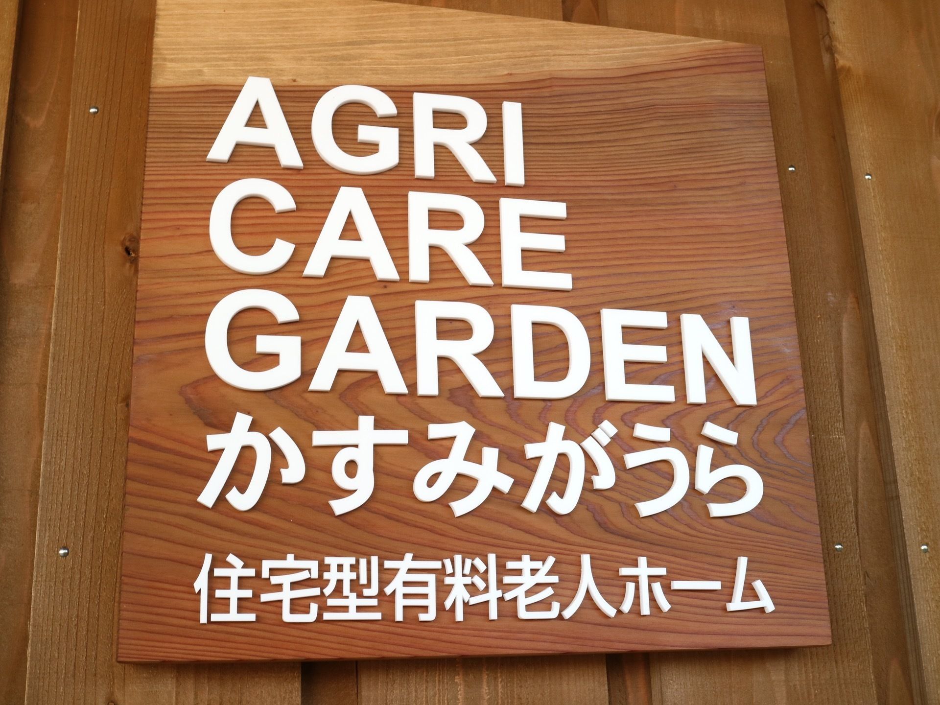 壁に木製の看板が取り付けられ、施設名や施設の種類が明記されている。焦げ茶色の板に、白字で書かれていて読みやすい。