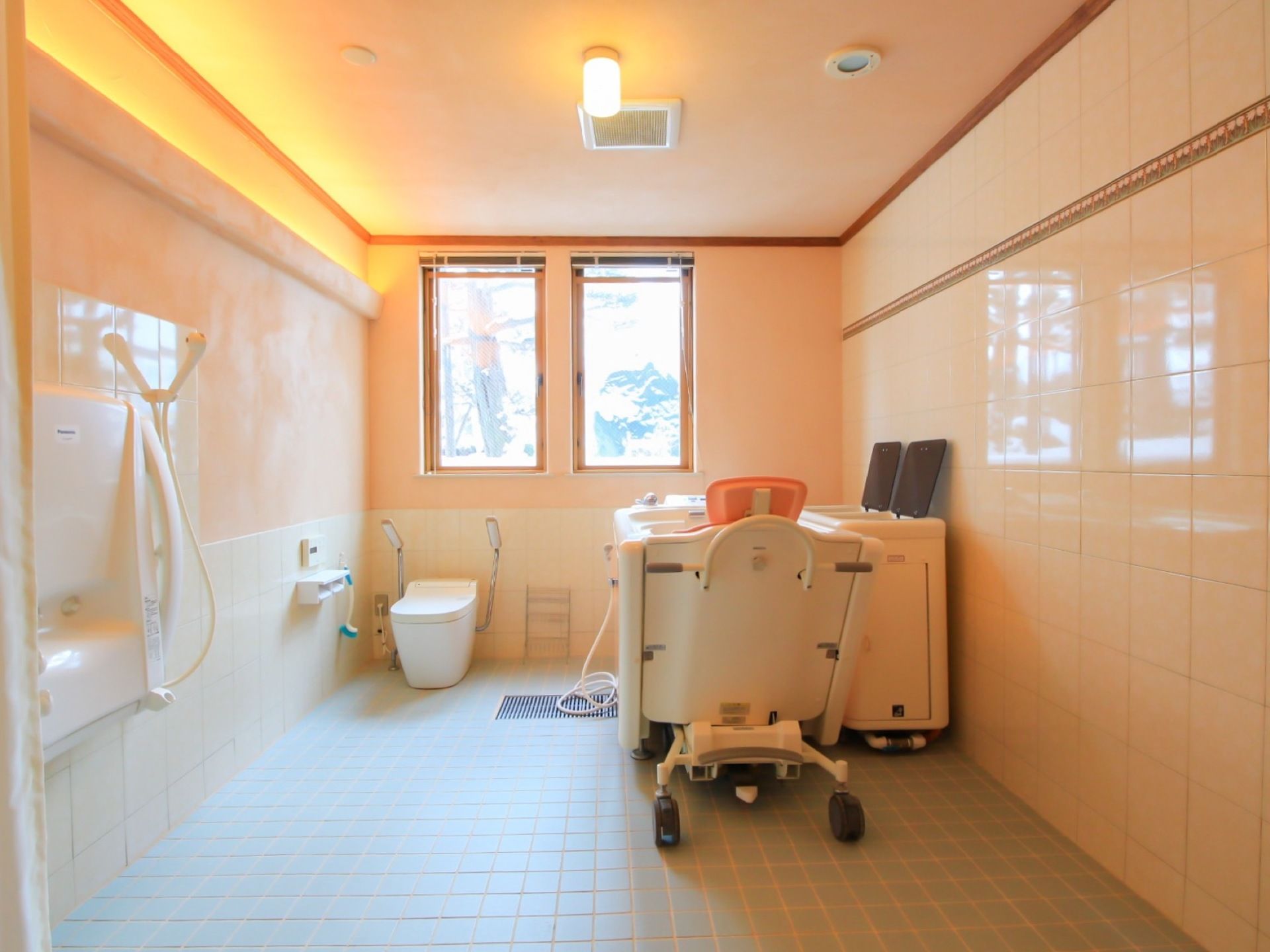 縦長の小窓が２つ設置された浴室の床はタイルが敷かれている。窓の下に洋式トイレと浴槽が並べて設置されている。