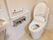 白を基調とした、清潔感のあるトイレである。白い壁にＬ字型の手すりが取付けられており、その下にはペーパーホルダーがある。