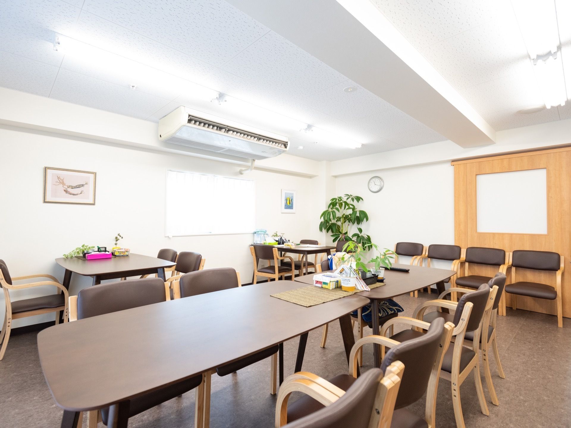 食堂と共有スペースを兼ねた大きな部屋が用意されている。各テーブルには箱のティッシュや鉢植えの緑が置かれている。
