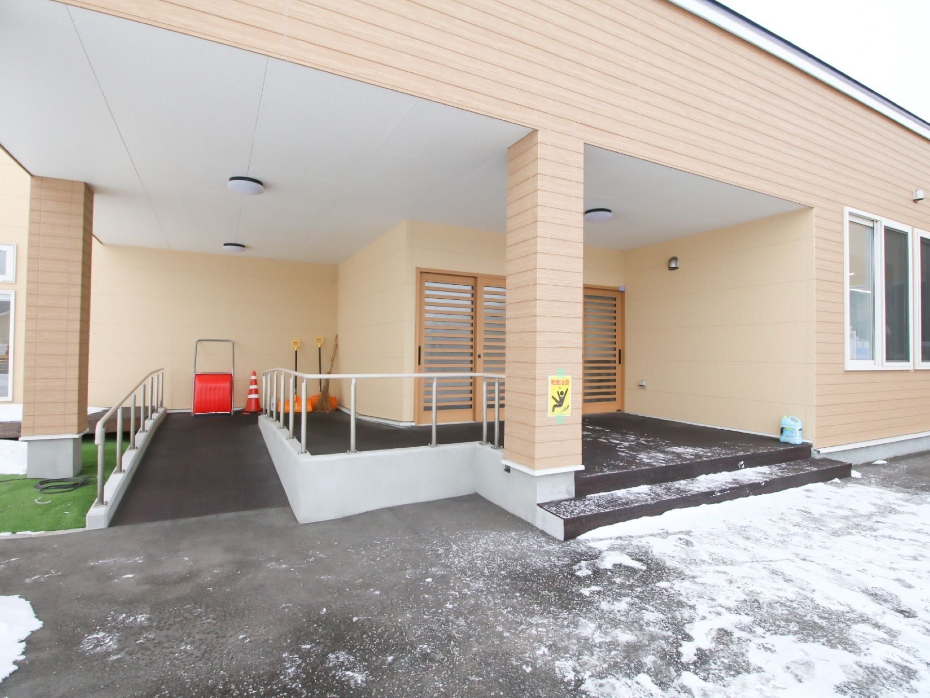 外から見た施設正面玄関。ドアの前にはステップがあり、左のスロープは除雪用具を置くスペースにもなっている。