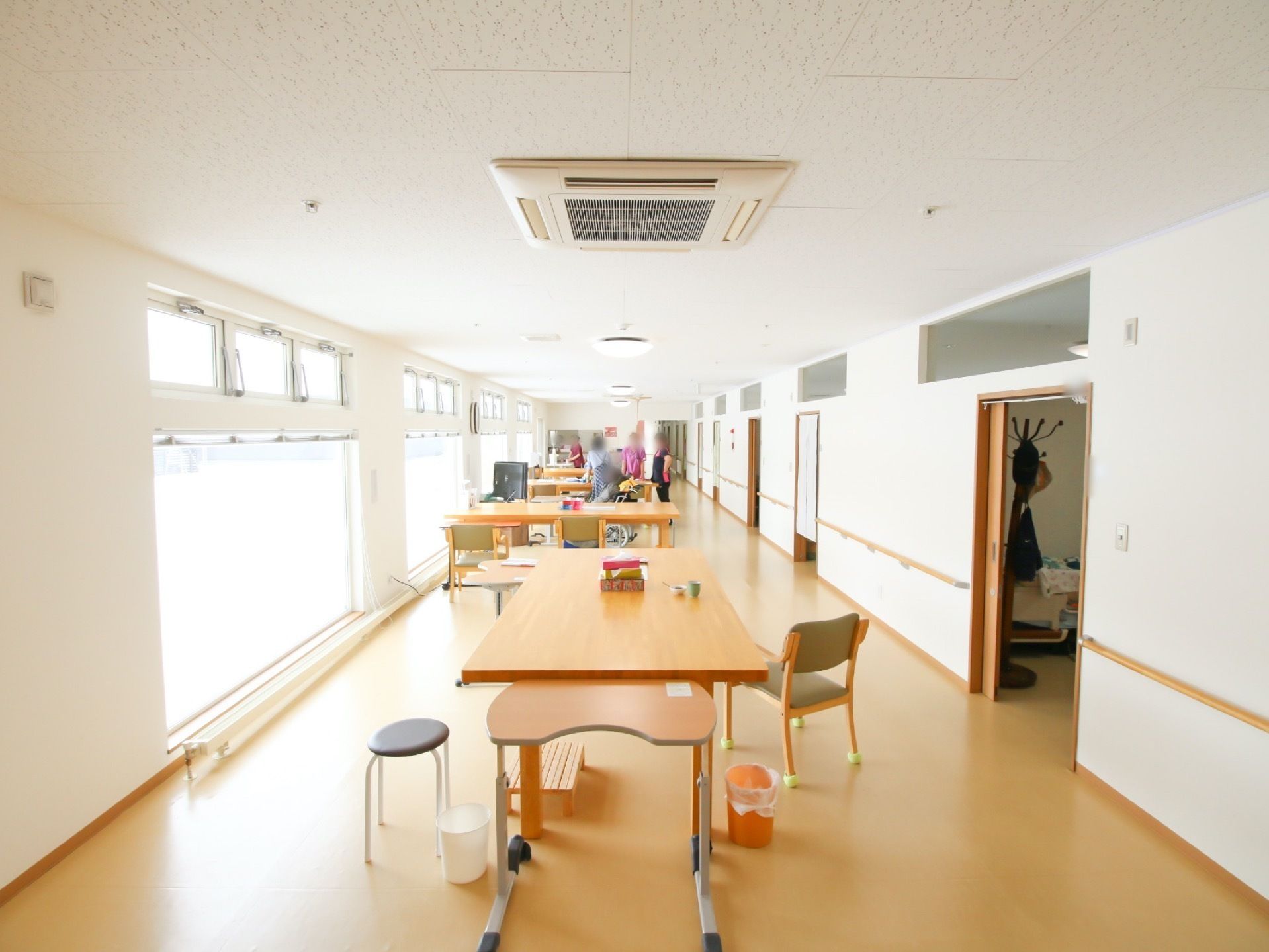 食堂や共有リビングなど、多目的に利用されている広い部屋。テーブルは、床の色に合わせたものが選ばれている。