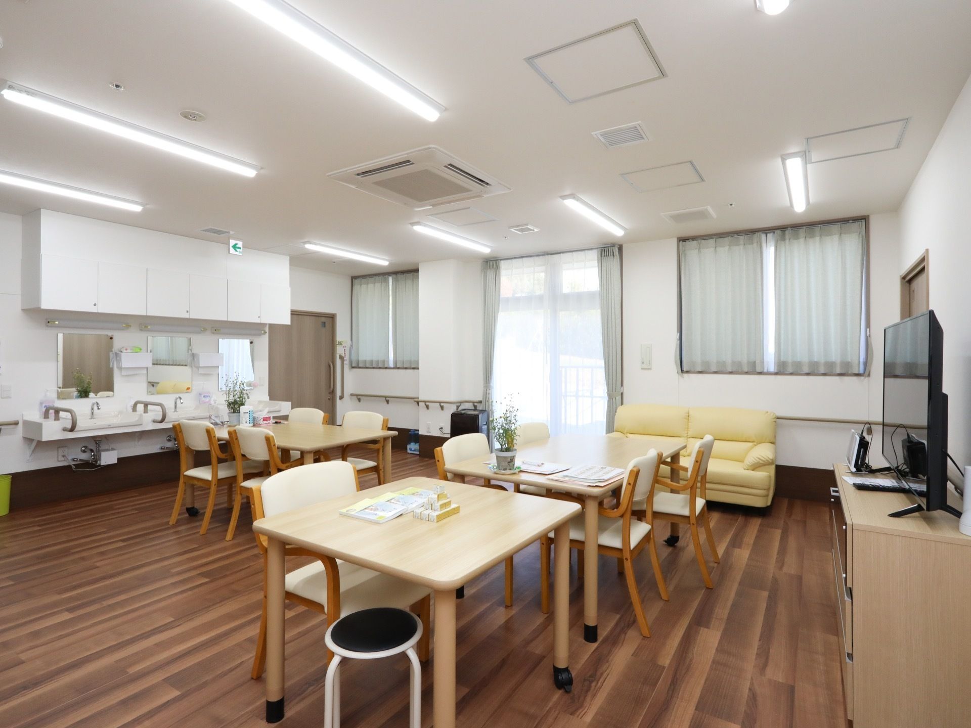 広々とした開放感のある食堂である。大型液晶テレビや４人掛けのダイニングテーブルセット、洗面スペースが完備されている。