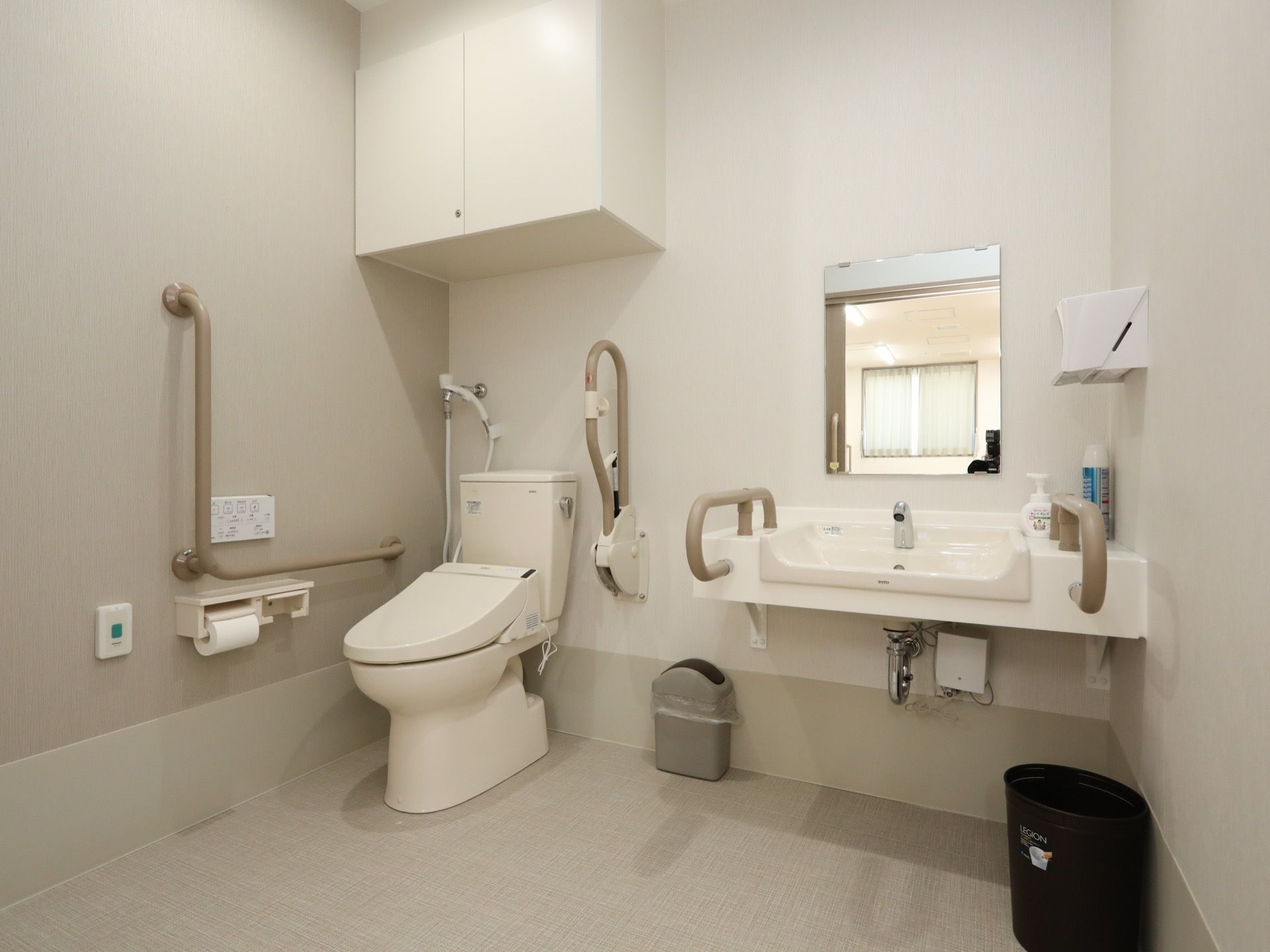 白を基調とした十分なスペースのあるトイレである。温水洗浄便座や手すり、洗面スペースが完備されている。