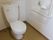 便器、手すり、トイレットペーパーホルダーや壁紙は清潔感のある白で統一している。床面の暗いトーンがアクセントなり落ち着きもある。