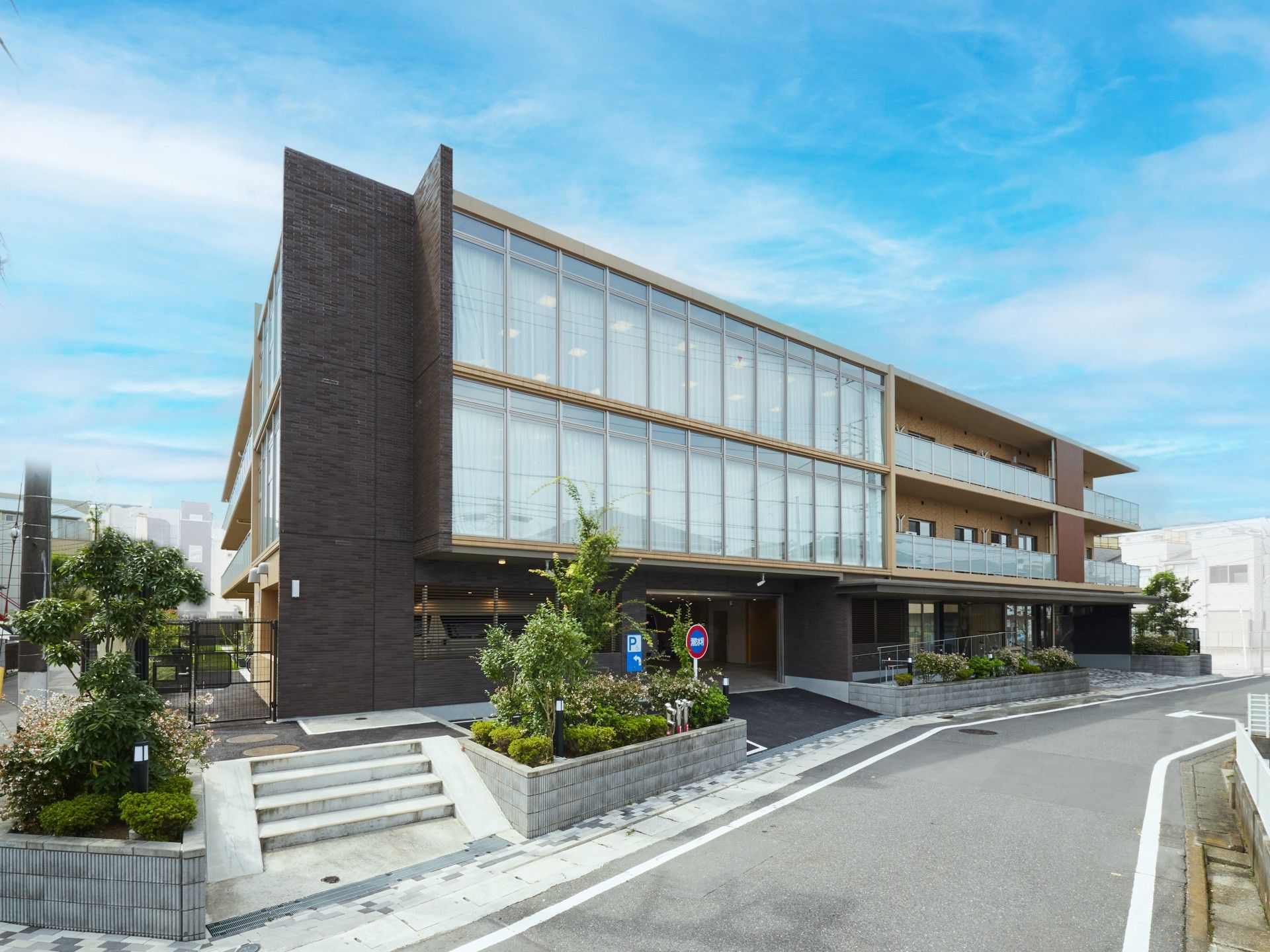 3階建ての建物はベランダ付きで、ガラス張りの明るい雰囲気。駐車スペースもある。