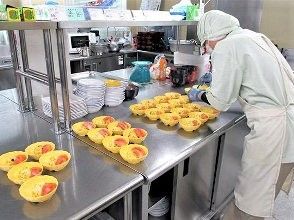 きれいに整理整頓された厨房で、スタッフが黄色い器に料理を盛り付けている。