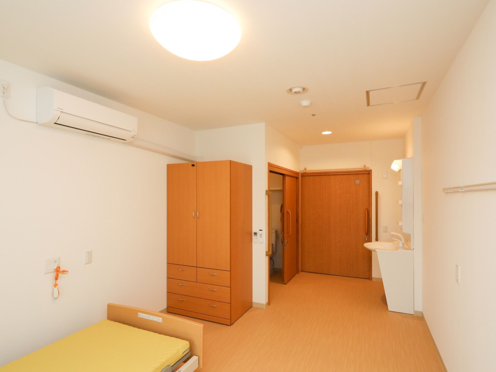 約11.7畳の居室である。エアコンや洗面化粧台、トイレが完備されており、介護ベッドとクローゼットが壁際に置かれている。