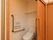 温水洗浄便座や呼び出しボタン、L型手すりを完備した居室のトイレである。扉には、開閉が楽なスライドドアを採用している。