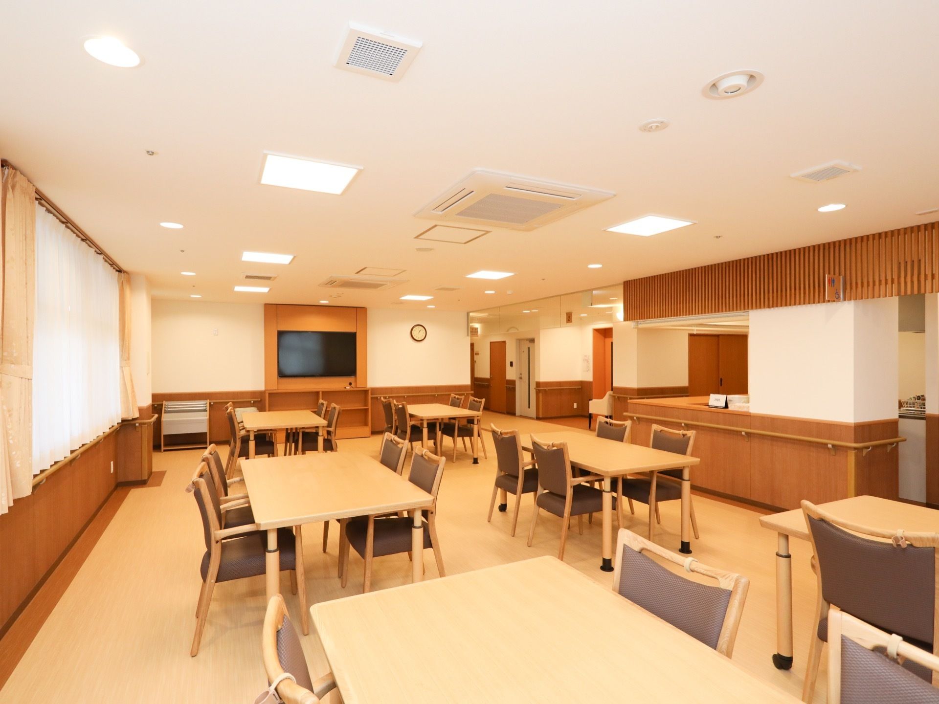 食堂は明るく開放的な空間になっており、４人掛けのダイニングテーブルが複数配置されている。壁に大型テレビが設置されている。