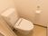 白を基調とした清潔感のある個室トイレである。壁には、緊急通報装置やペーパーホルダーが取り付けられている。