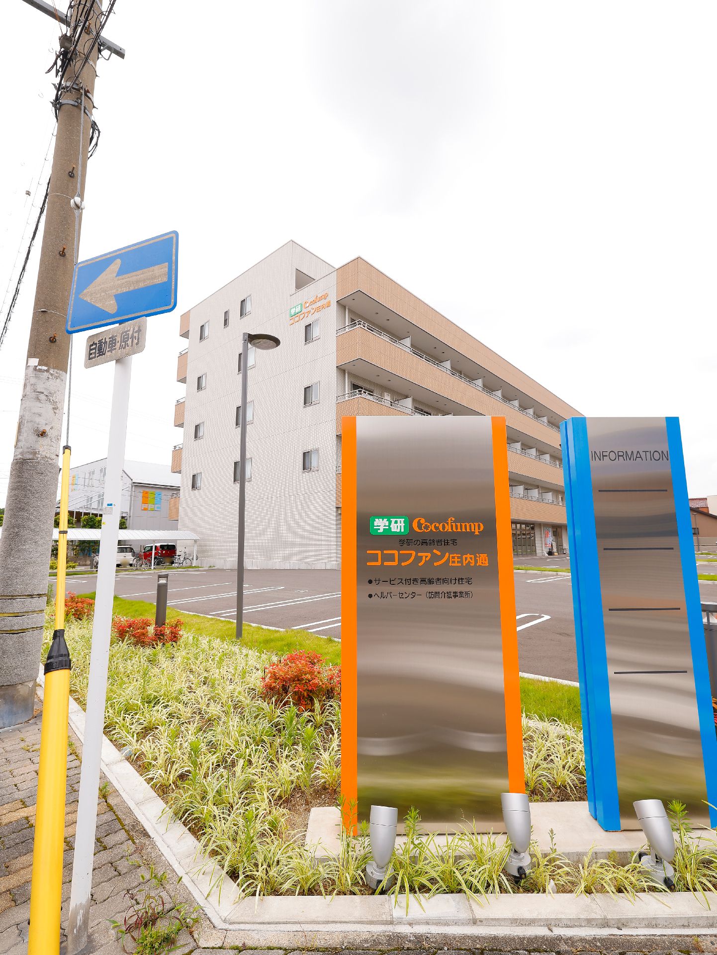 道路に面した敷地内に設置されている、施設の名称・ロゴが書かれた看板